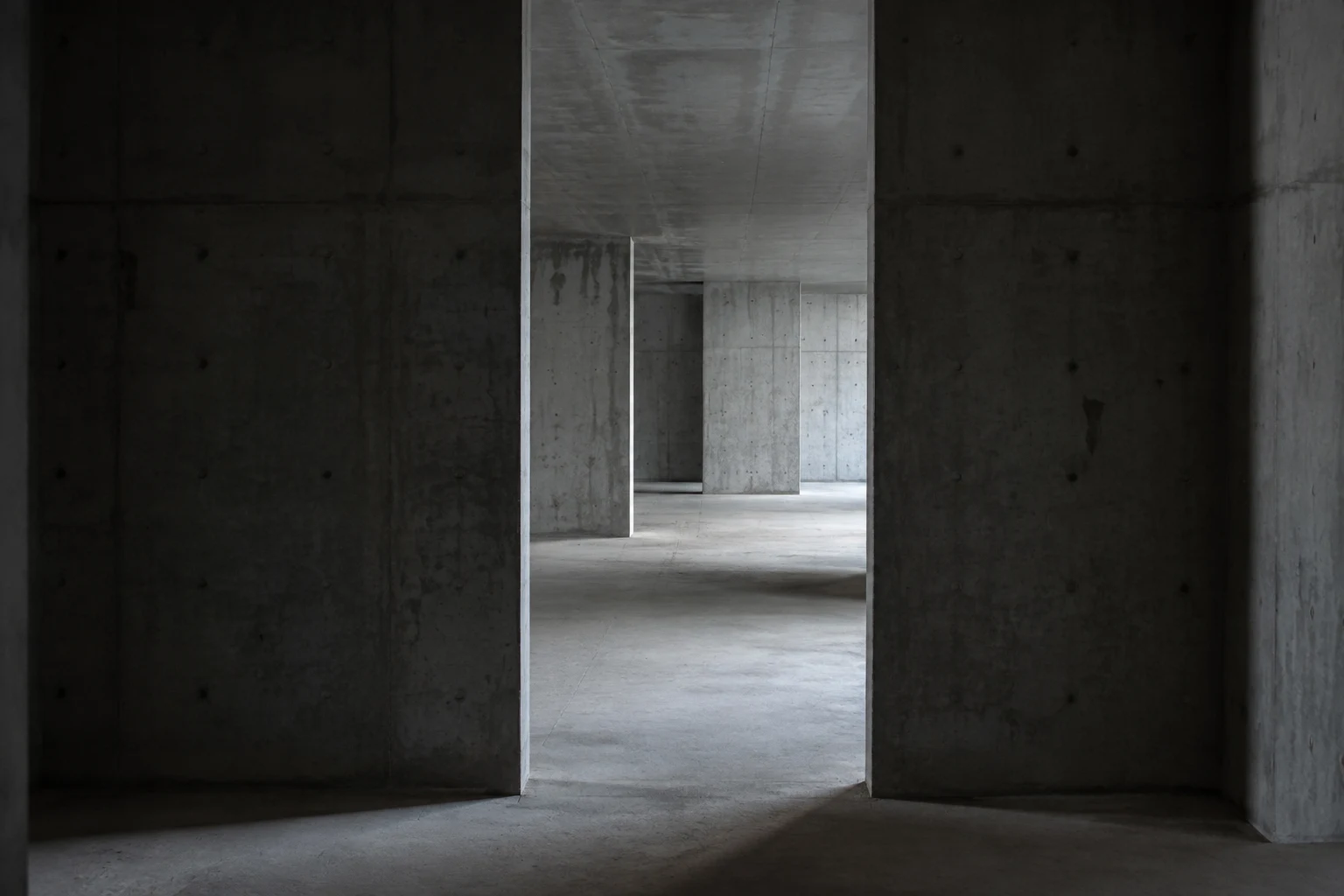 Illustrative concrete interior with rooms extending beyond an open doorway